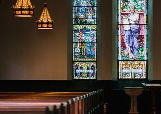 empty church pews facing stained glass windows 